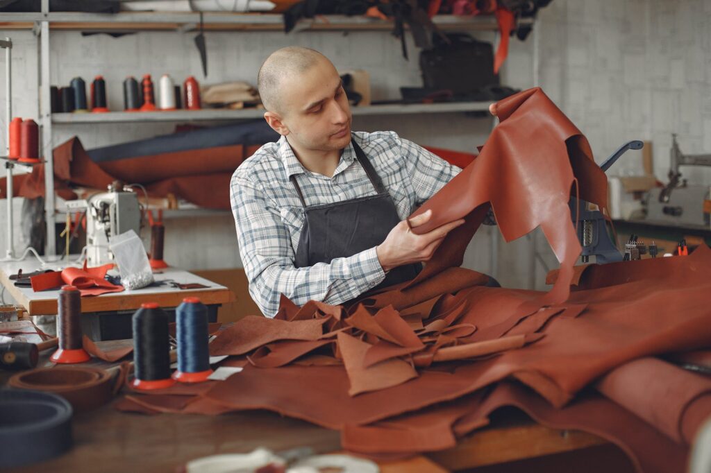 Artisan taking care and repair leather piece in workshop